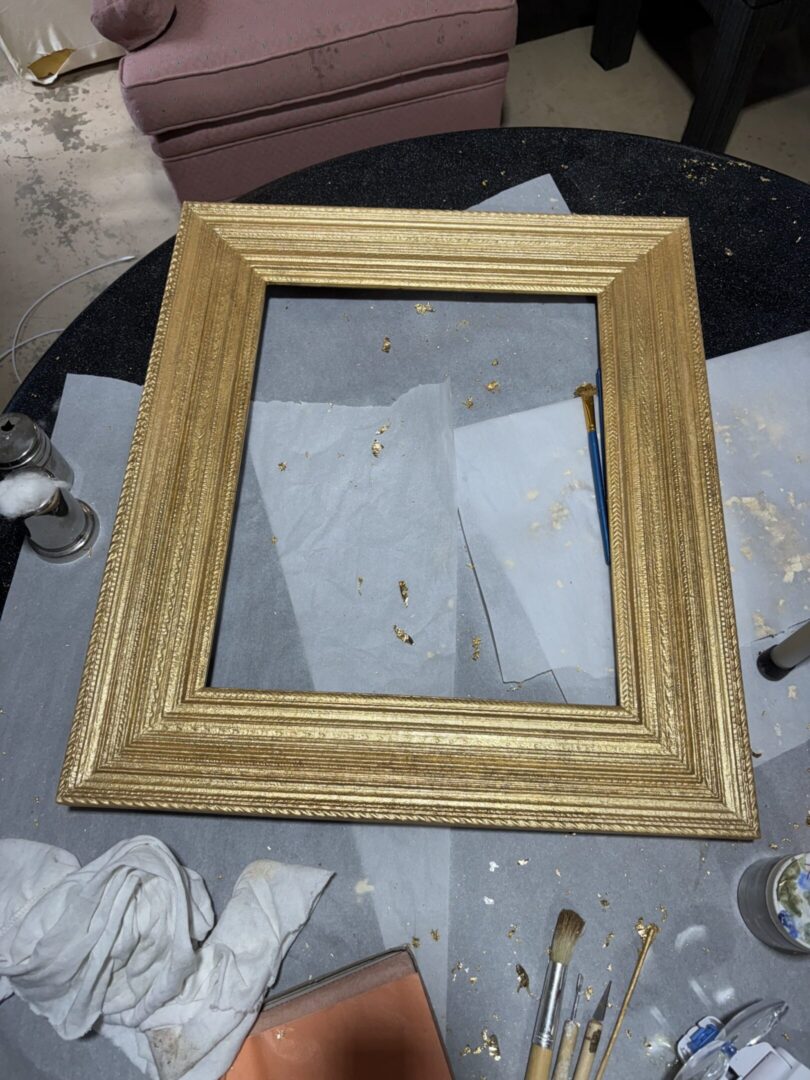 Gold ornate picture frame on messy worktable
